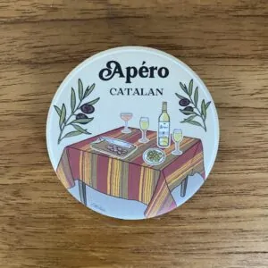 Magnet illustré représentant une table d'apéritif catalane avec nappe rayée et spécialités régionales, création de Caroline Duboc