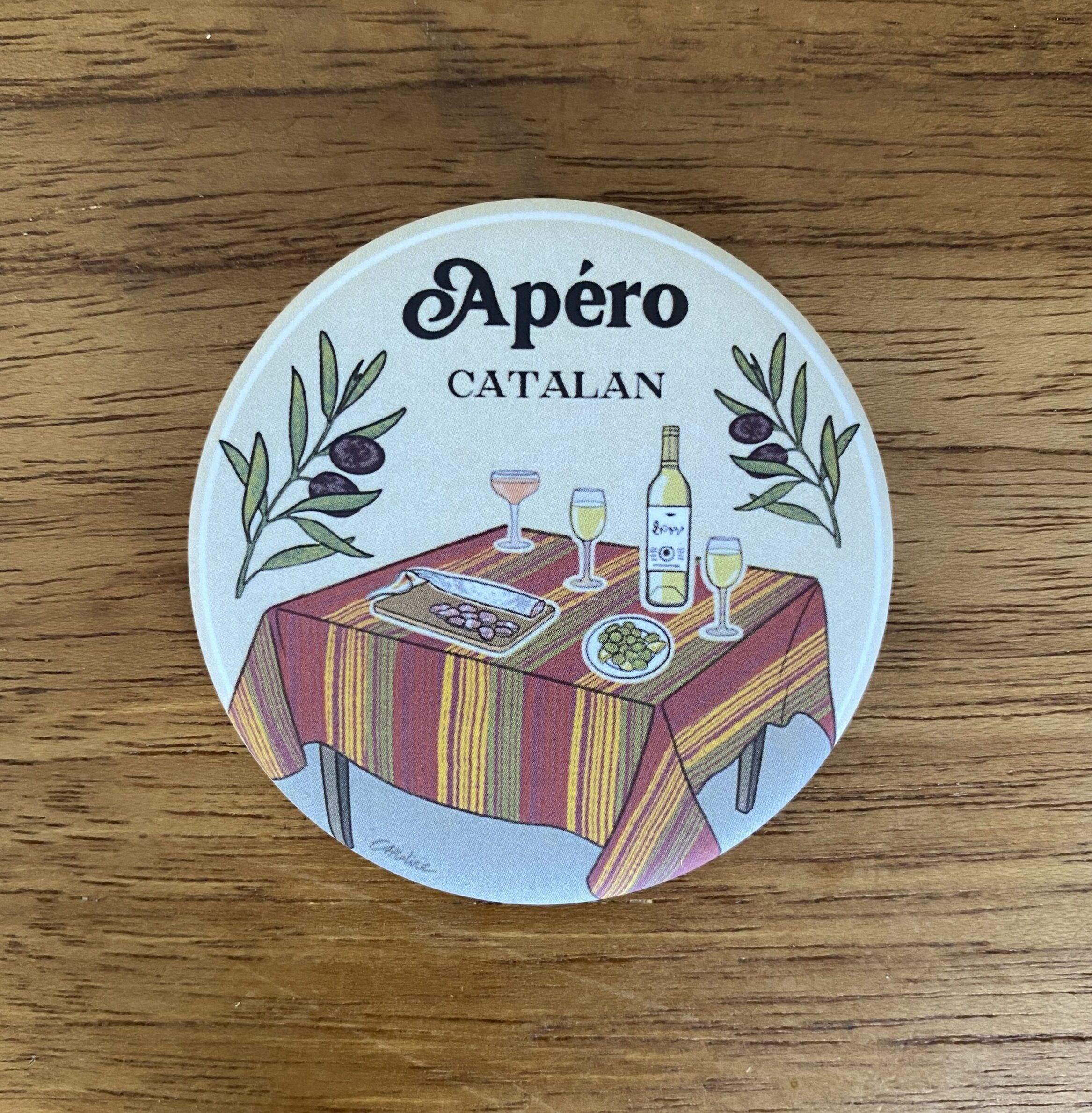 Magnet illustré représentant une table d'apéritif catalane avec nappe rayée et spécialités régionales, création de Caroline Duboc